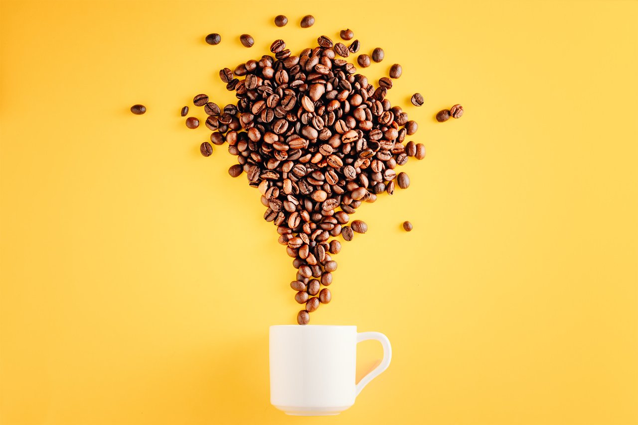 Coffee cup with beans on yellow background